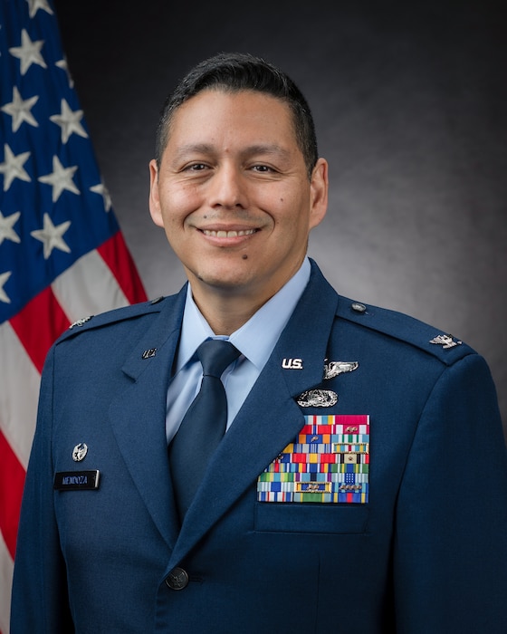 An Airman poses for a photo in front of an American flag.