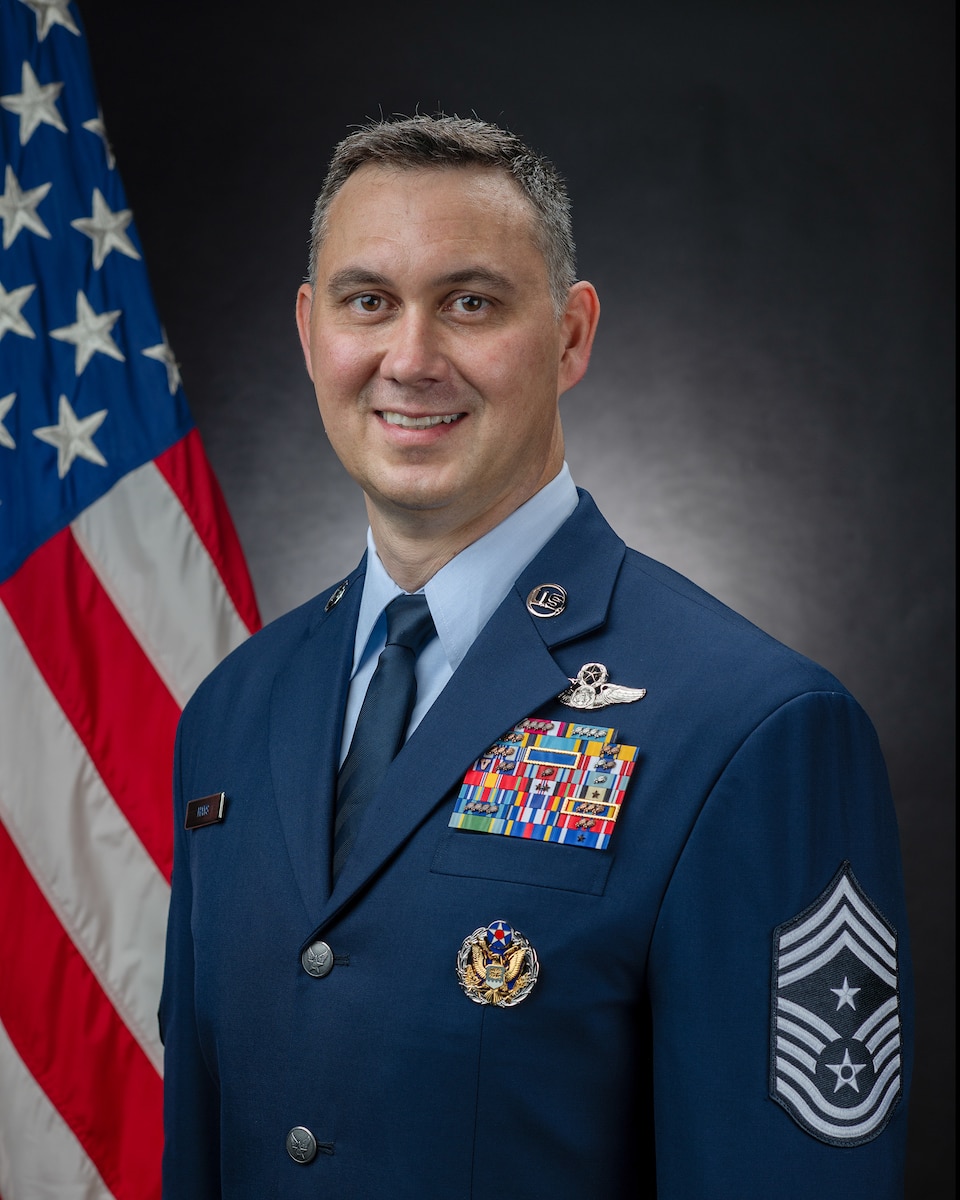 An Airman poses for a photo in front of an American flag.