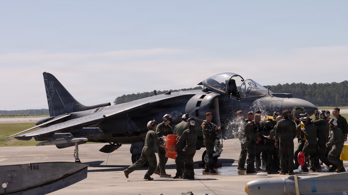 U.S. Marines with Marine Attack Squadron (VMA) 223, Marine Aircraft Group 14, 2nd Marine Aircraft Wing, and families celebrate with water and champagne at Marine Corps Air Station Cherry Point, June 3, 2026. The “sundown” of the AV-8B Harrier II, an iconic aircraft that has supported joint and Marine Corps operations for over 40 years, also represents the dawn of a new era; it paves the way for 2nd MAW’s full transition to the F-35B and C Lightning II. VMA-223 is the U.S. Marine Corps' last operational Harrier squadron.