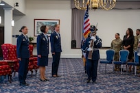 A photo of an Air Force Col., Maj. and Lt. Col. standing at attention while the Honor guard post the colors.