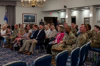 a group of guesting sitting down on chairs smiling and listening to the speaker.