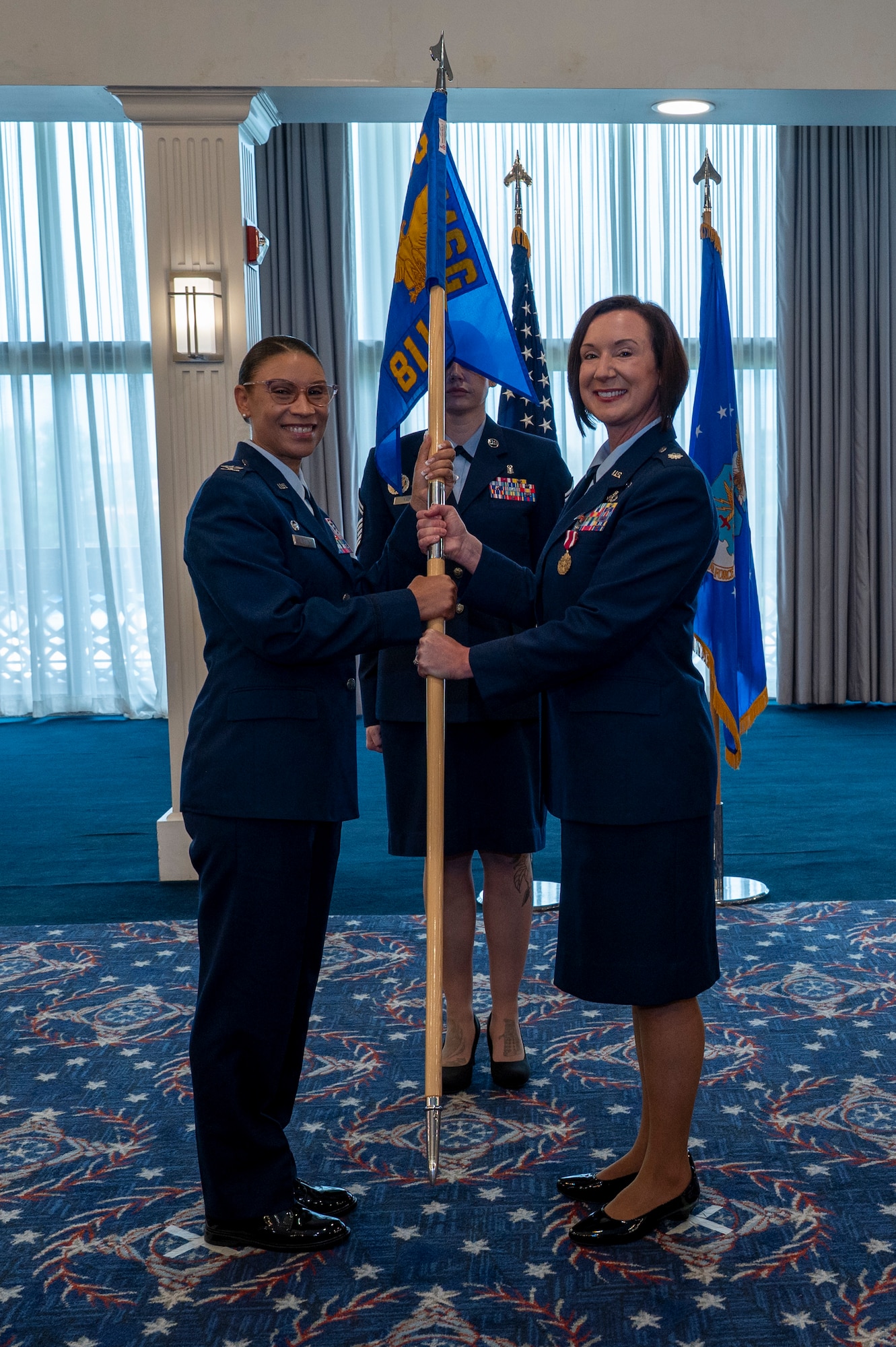 A photo of Air Force Col. and lt. Col. holding a guidon facing the camera.