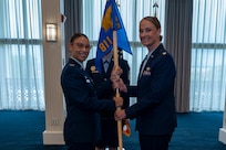 A photo of an Air Force Col. and Maj. holding a guidon together facing the  camera.