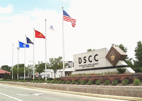 Outside photo of DSCC sign to the right and flags to the left.
