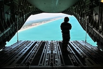 A photo of a loadmaster opening the cargo ramp of a C-17 Globemaster III cargo plane.