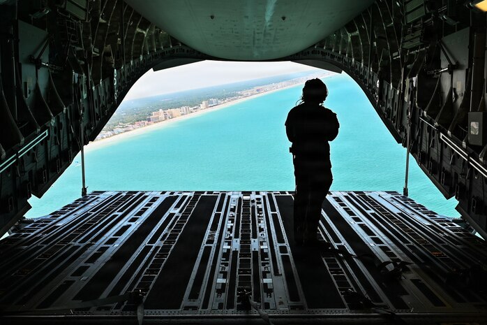 A photo of a loadmaster opening the cargo ramp of a C-17 Globemaster III cargo plane.