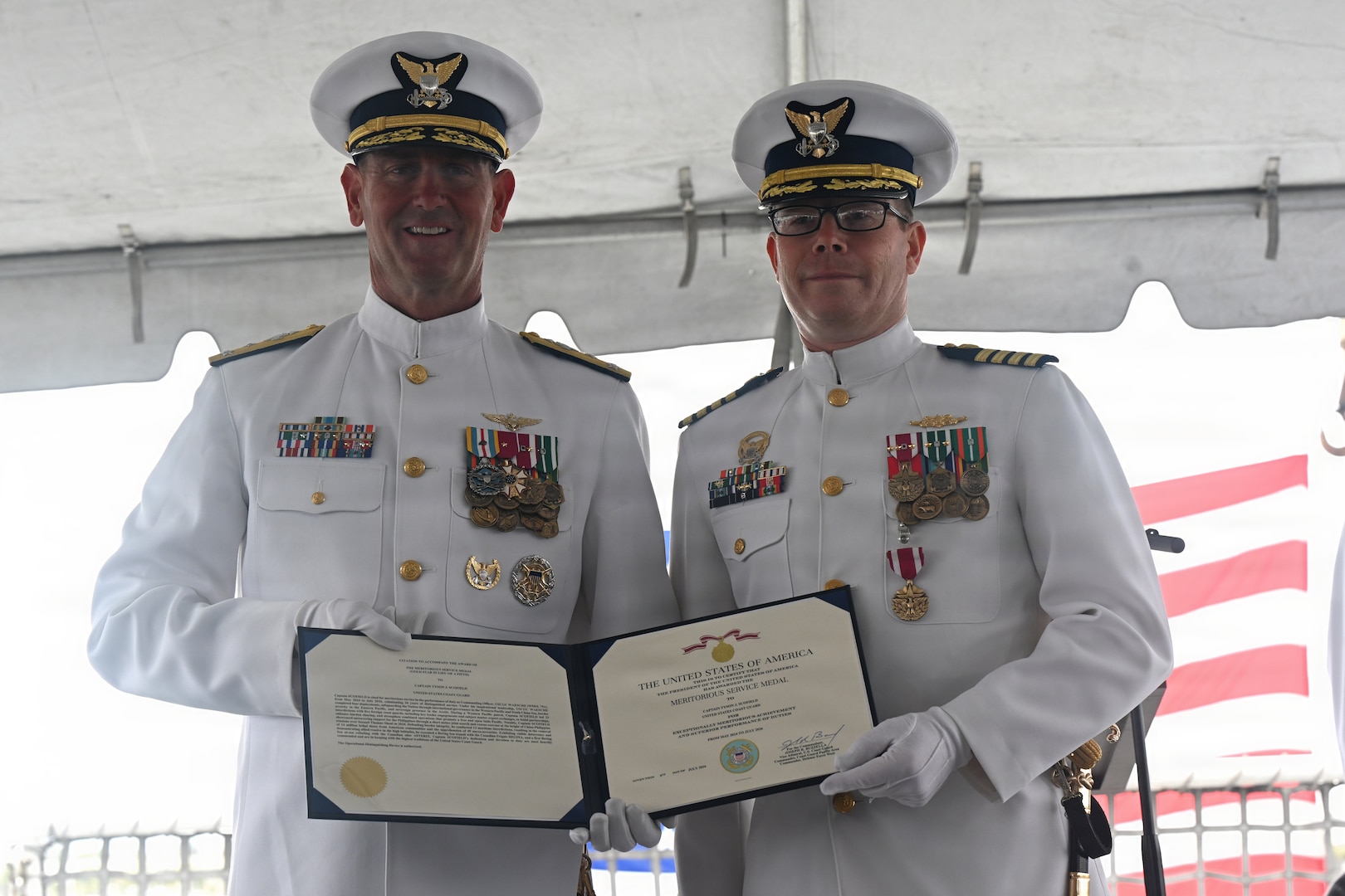 U.S. Coast Guard Vice Adm. Joseph R. Buzzella, left, presents a Meritorious Service Medal to Capt. Tyson J. Scofield during the USCGC Waesche’s (WMSL 751) change-of-command ceremony at Coast Guard Island in Alameda, California, July 9, 2026. Scofield led Waesche through several high latitude deployments, including a 105-day, 21,000-nautical mile Arctic patrol and a 113-day winter patrol in the Bering Sea to enforce maritime laws and project U.S. Presence. (U.S. Coast Guard photo by Petty Officer 3rd Class Danish Khan.)