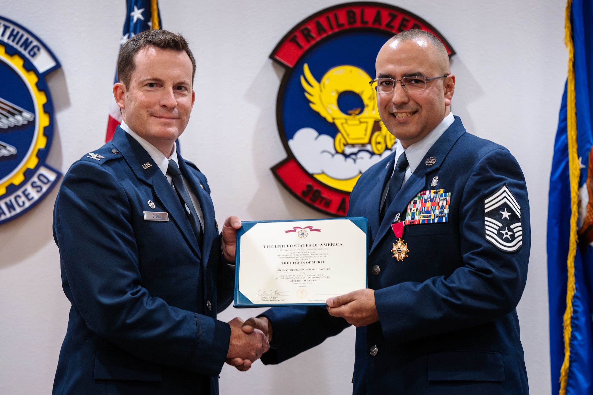 U.S. Air Force Col. Justin Diehl, 317th Airlift Wing commander, presents the Legion of Merit to Chief Master Sgt. Martin Castillo, outgoing 317th AW command chief, during a change of responsibilities ceremony at Dyess Air Force Base, Texas, June 12, 2026. During the ceremony the responsibilities of senior enlisted leader for the 317th AW changed from Chief Master Sgt. Martin Castillo to Brian Castillo. (U.S. Air Force photo by Senior Airman Jade M. Caldwell)