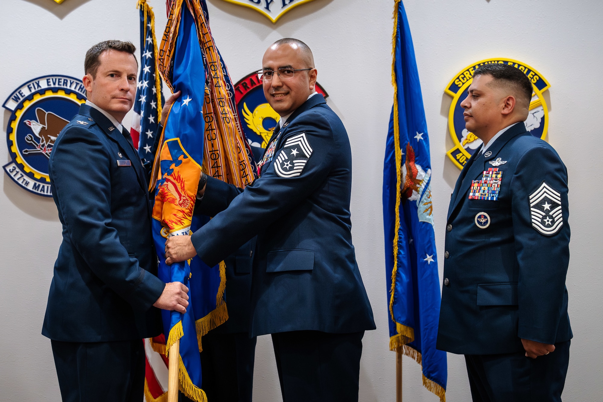 U.S. Air Force Chief Master Sgt. Martin Castillo, center, outgoing 317th Airlift Wing command chief, passes the guidon to Col. Justin Diehl, left, 317th AW commander, during a change of responsibilities ceremony at Dyess Air Force Base, Texas, June 12, 2026. The change of responsibility ceremony symbolizes the formal transfer of enlisted leadership through the passing of the unit's colors, representing the senior enlisted leader's responsibility for the discipline, readiness and welfare of the enlisted force. (U.S. Air Force photo by Senior Airman Jade M. Caldwell)