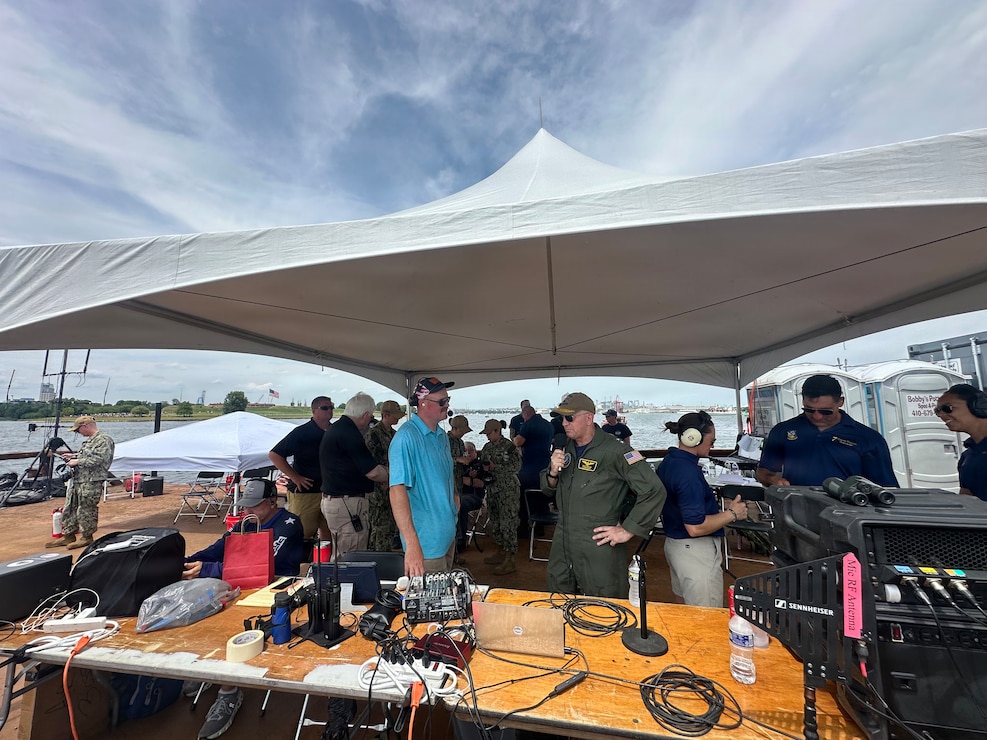 Rear Adm. David Faehnle, Commandant, Naval District Washington, speaks with Jake Stuart, air show announcer, during the air show portion of Sail 250 Maryland and Airshow Baltimore