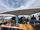 Rear Adm. David Faehnle, Commandant, Naval District Washington, speaks with Jake Stuart, air show announcer, during the air show portion of Sail 250 Maryland and Airshow Baltimore