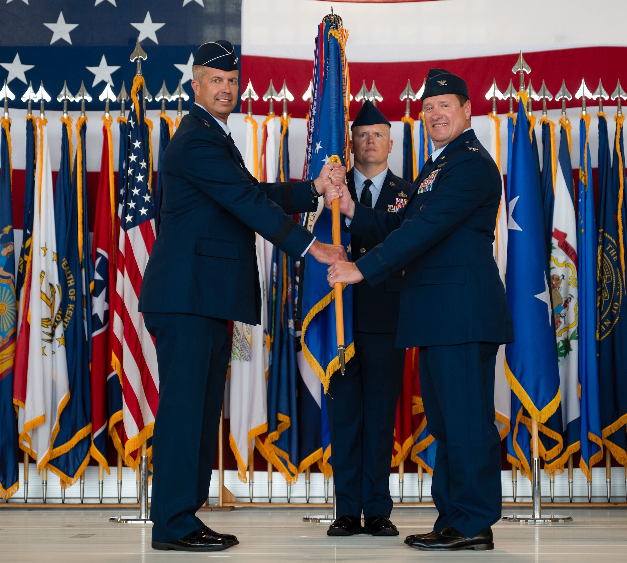 U.S. Air Force Maj. Gen. Ty Neuman, 8th Air Force and Joint-Global Strike Operations Center commander, left, relinquishes the guidon to U.S. Air Force Col. John Burrell, 5th Bomb Wing (BW) incoming commander, right, during a change of command ceremony at Minot Air Force Base, North Dakota, July 9, 2026. As the incoming commander, Burrell is responsible for leading the 5th BW’s B-52H Stratofortress operations and ensuring the wing remains ready to provide global strike capabilities in support of Air Force Global Strike Command’s strategic deterrence mission. (U.S. Air Force photo by Airman 1st class Anthony Ramey)