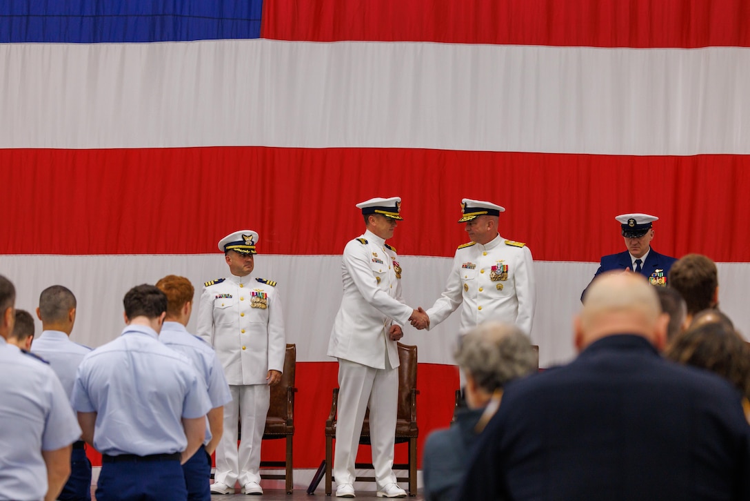 Coast Guard Cmdr. Rand Semke, center, outgoing commanding officer of Coast Guard Air Station Sitka, shakes hands with Rear Adm. Ralph Little, right, commander of Coast Guard Arctic District, at the air station’s change-of-command ceremony in Sitka, Alaska, July 10, 2026. Cmdr. Joseph Plunket assumed command from Semke following his two-year tour as the air station’s commanding officer. 

(Courtesy photo by Auxiliarist Don Kluting)