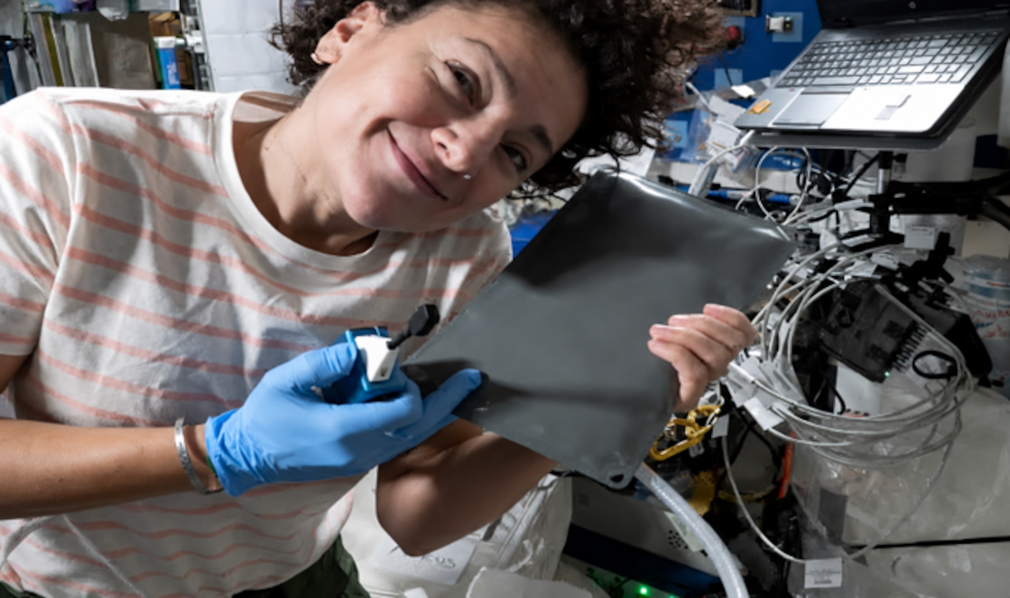 NASA astronaut Jessica Meir poses with the Airion Advanced Inflight Relief Universal System (AIRUS) aboard the International Space Station on an unknown date. The AIRUS bladder relief system, originally developed through the AFWERX Sky High Relief Challenge to improve in-flight bladder relief for military aviators, launched aboard NASA's SpaceX Crew-12 mission to the International Space Station on Feb. 13, 2026, as a technology demonstration. The effort highlights how Air Force-driven innovation transitioned from addressing an operational need for Airmen to supporting long-duration human spaceflight. (Courtesy photo/NASA)
