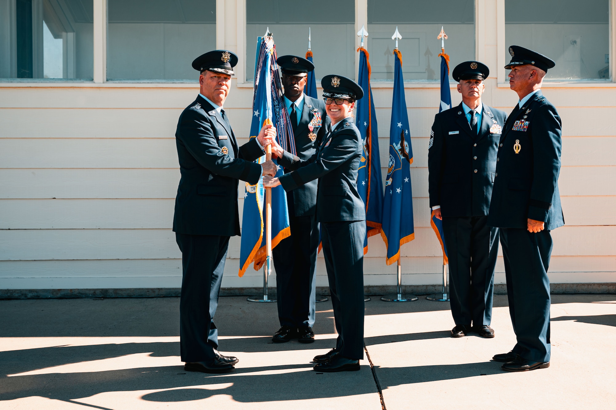 U.S. Air Force Gen. S.L. Davis, commander of Air Force Global Strike Command, receives the 20th Air Force Guidon from Maj. Gen. Stacy Jo Huser, outgoing 20th AF commander at the 20th AF change of command at F.E. Warren Air Force Base, Cheyenne, Wyoming, July 10, 2026. Following the change of command, Huser retired after 30 years of dedicated service to the USAF. (U.S. Air Force photo by Senior Airman Mattison Cole)