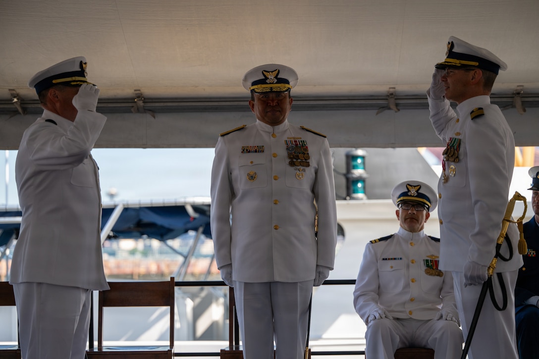 U.S. Coast Guard Capt. Michael Hunt (left), incoming commanding officer of Coast Guard Sector Puget Sound, renders a salute to Capt. Mark McDonnell (right), outgoing commanding officer of the sector, while Rear Adm. Arex Avanni (center), commander of the Coast Guard Northwest District, officiates the pass down during the Coast Guard Sector Puget Sound change-of-command ceremony in Seattle, Washington, July 10, 2026