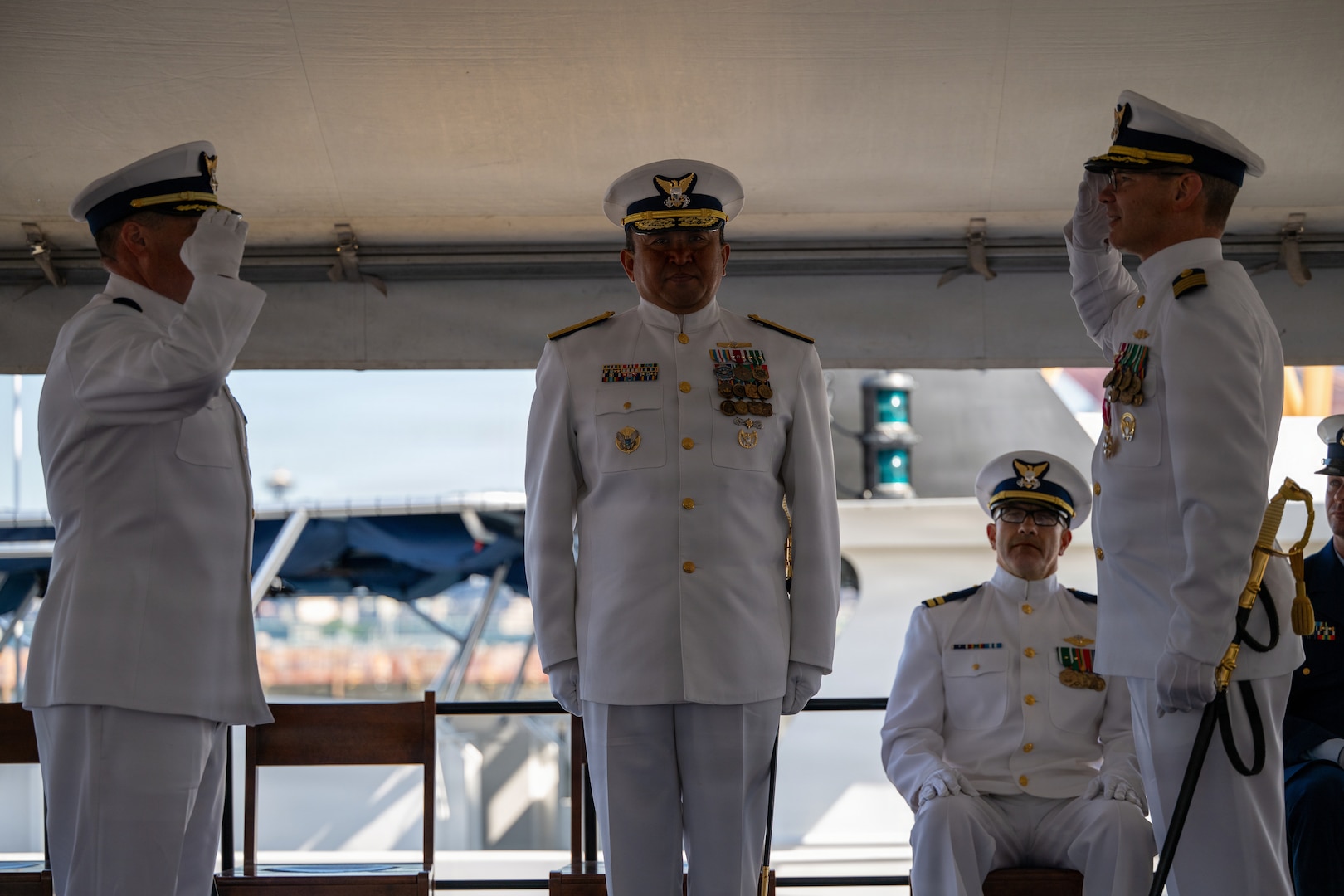 U.S. Coast Guard Capt. Michael Hunt (left), incoming commanding officer of Coast Guard Sector Puget Sound, renders a salute to Capt. Mark McDonnell (right), outgoing commanding officer of the sector, while Rear Adm. Arex Avanni (center), commander of the Coast Guard Northwest District, officiates the pass down during the Coast Guard Sector Puget Sound change-of-command ceremony in Seattle, Washington, July 10, 2026