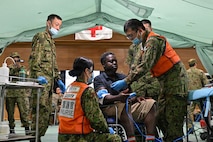 Japan Ground Self-Defense Force service members perform a medical assessment on a simulated casualty during a humanitarian assistance and disaster relief scenario as part of Resolute Dragon 26 at Camp Miyako, Okinawa, Japan on June 26, 2026. Resolute Dragon is an annual bilateral exercise in Japan that strengthens the command, control, and multi-domain maneuver capabilities of U.S. Marines in III Marine Expeditionary Forces and Japan Self-Defense Forces personnel, with a focus on controlling and defending key maritime terrain. (U.S. Marine Corps photo by Lance Cpl. Nathan Saucier)