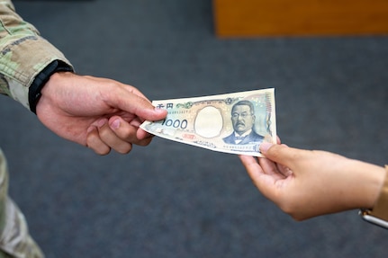 A 1,000 yen note is passed from a U.S. service member to a Japanese civilian at Yokota Air Base, Japan July 13, 2026.