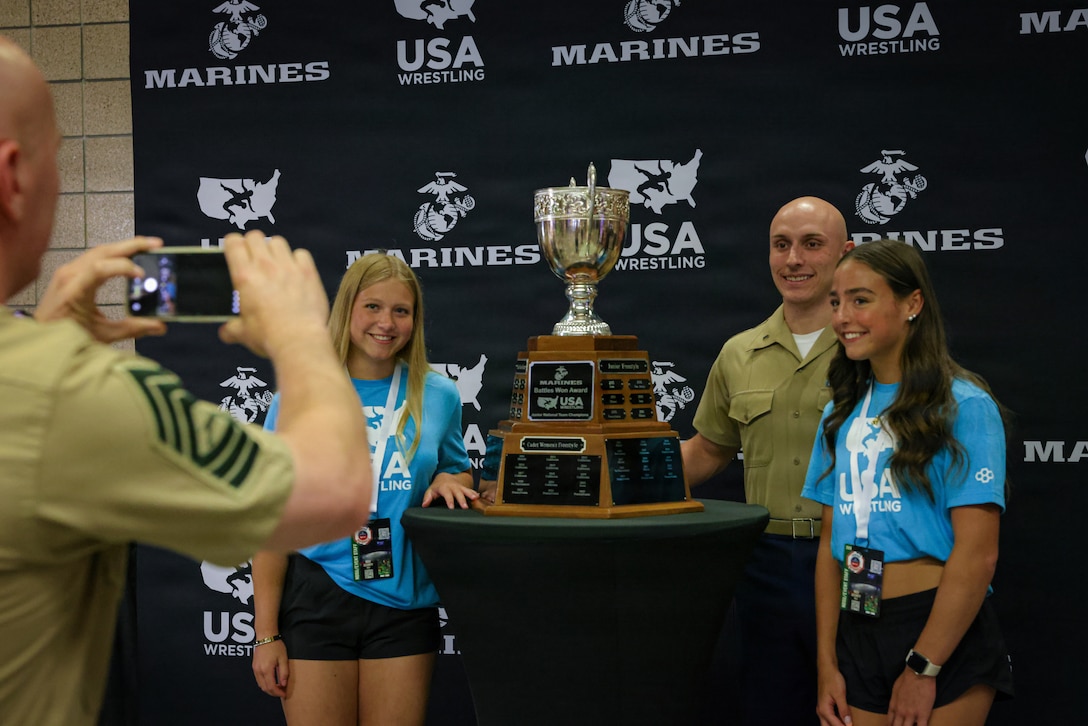 U.S. Marine Corps 1st Lt. August Rohmeyer, right, a budget operations officer with Marine Forces Special Operations Command, poses for a photo with USA Wrestling volunteers and the “Battles Won Award” during the U.S. Marine Corps Junior Nationals tournament in Fargo, N.D., July 11, 2026. This award is presented to the top team in each premier division of the boys and girls freestyle and Greco-Roman. This year marks the historic 10th anniversary of the partnership between the U.S. Marine Corps and USA Wrestling. (U.S. Marine Corps photo by Sgt. Aidan Hekker)