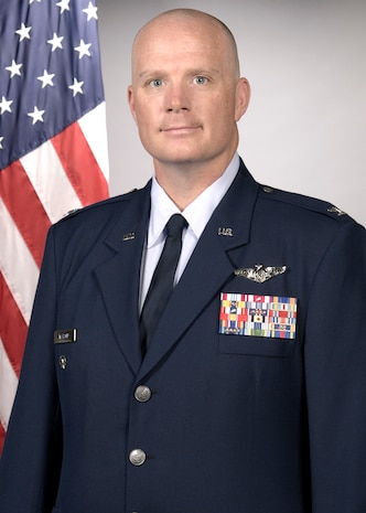 photo of US Airman standing in front of a US flag
