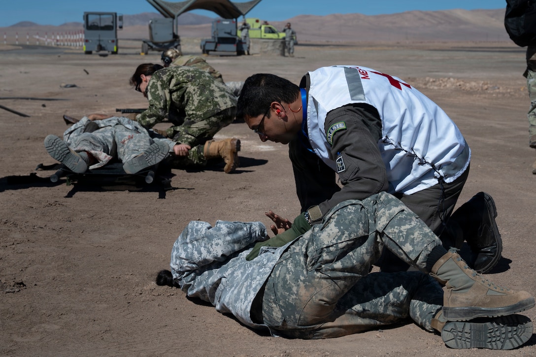 A man in a Brazil Medical military uniform crouches over a Paraguayan service member