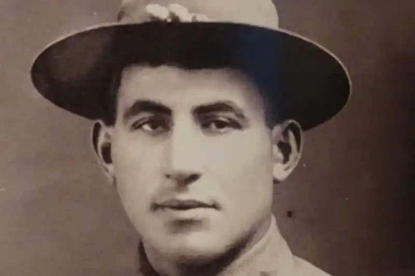 A black and white photo of a man as he poses in his military uniform.