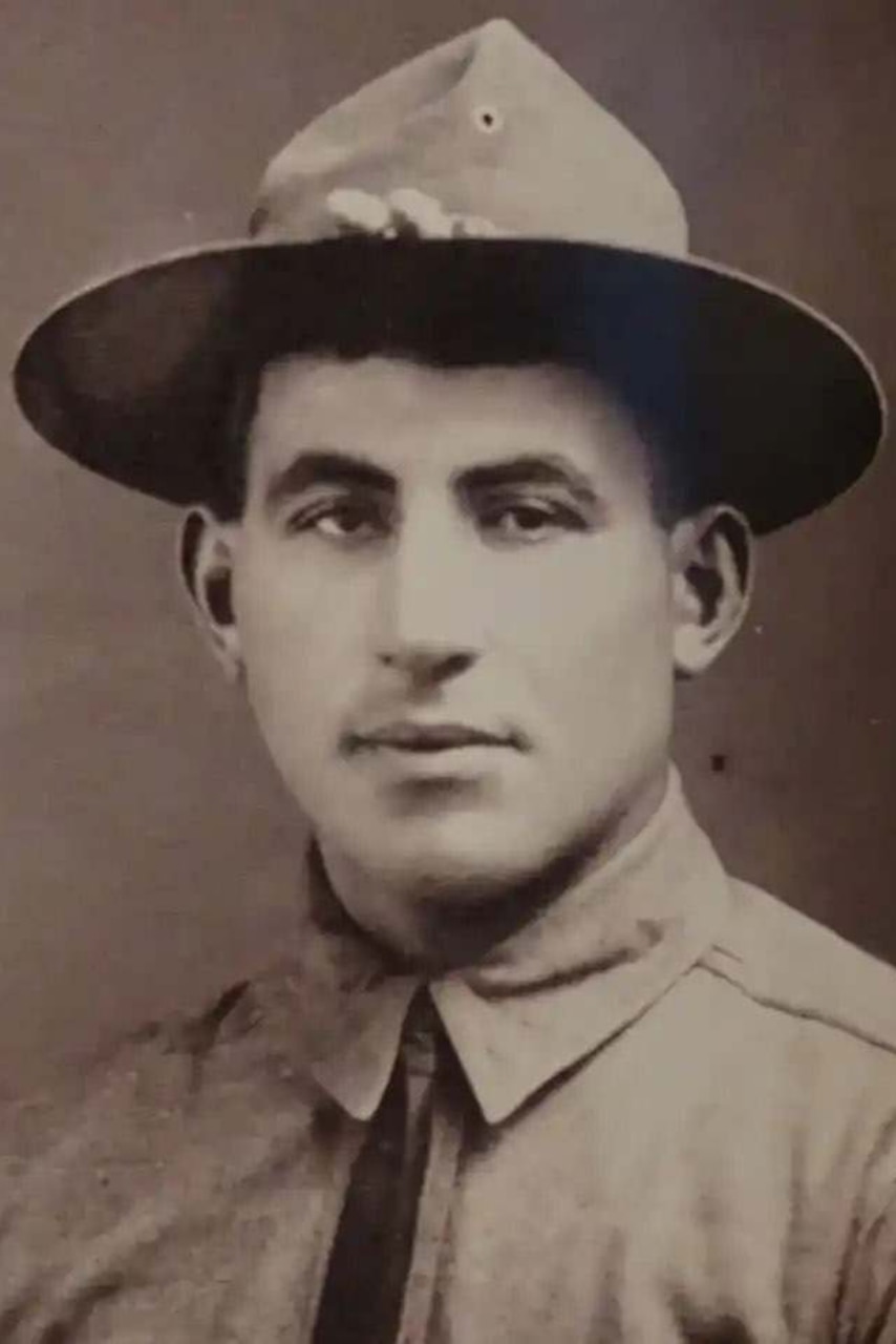 A black and white photo of a man as he poses in his military uniform.