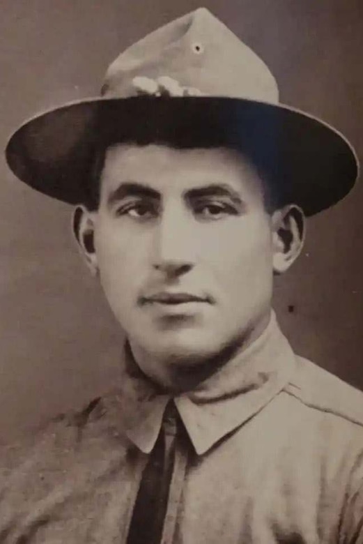 A black and white photo of a man as he poses in his military uniform.