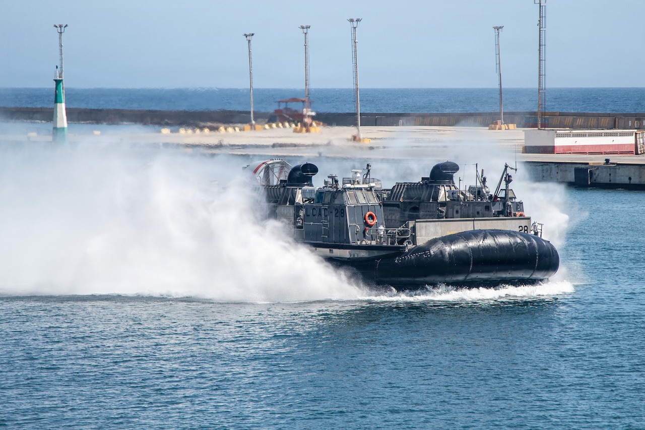 A landing craft sprays water in the air as it sails in the water.