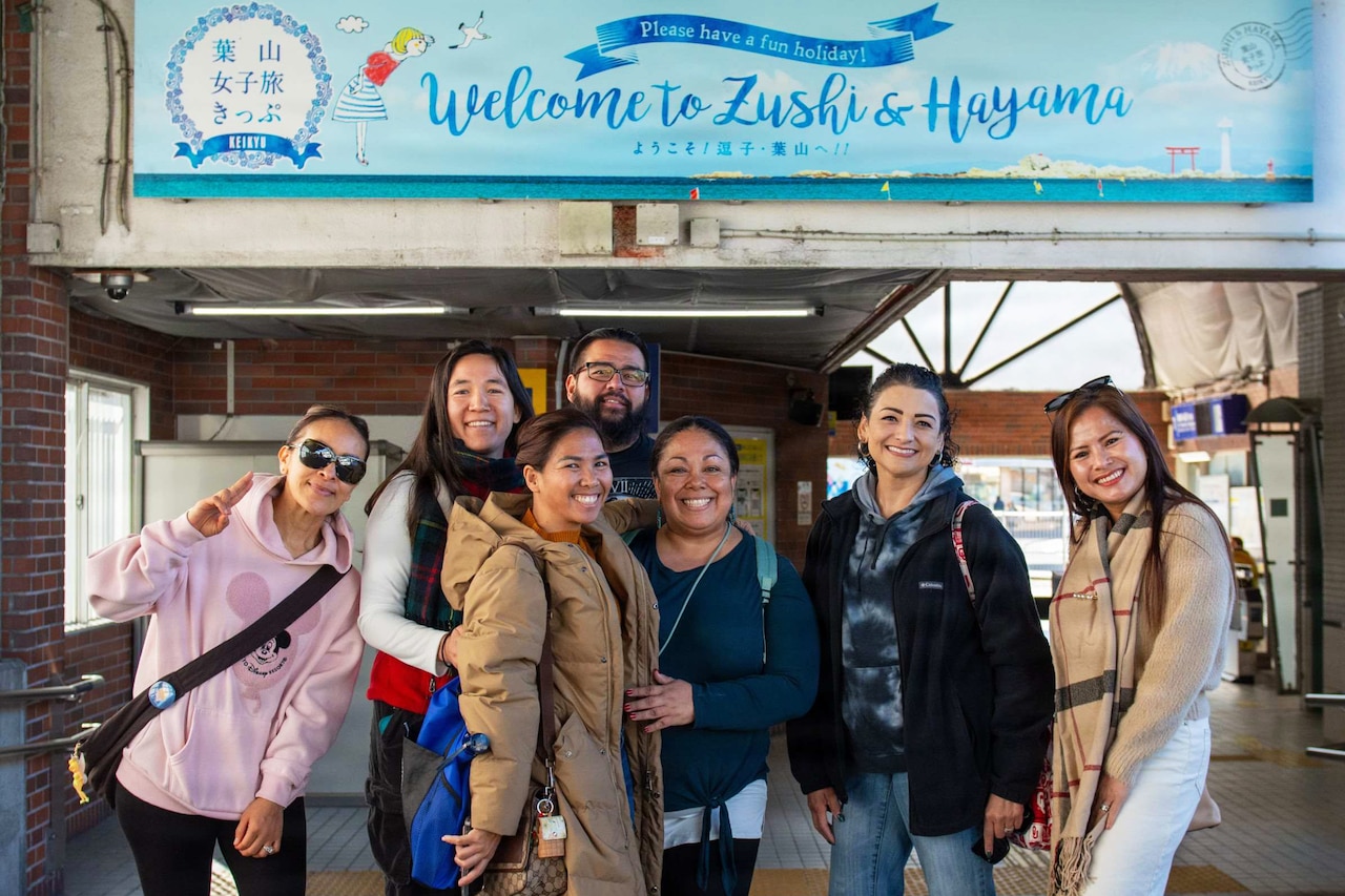 A group of people dressed in casual attire pose for a photo outside.