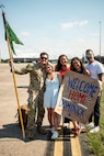 The guidon bearer for 643rd Military Police Company, Connecticut National Guard, poses for a photo with his family after returning from deployment at Bradley Air National Guard Base, East Granby, Connecticut, July 11, 2026.
