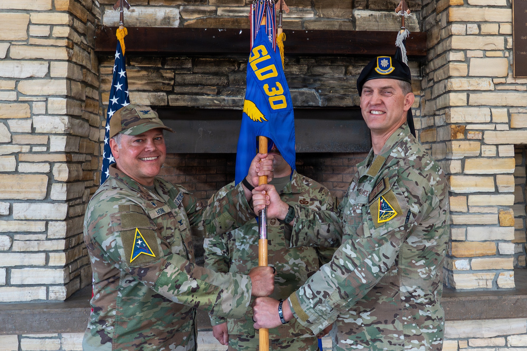Three people stand, two of them hold a flag