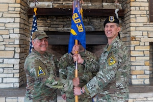 Three people stand, two of them hold a flag