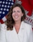 Portrait of a Caucasian female in a white business jacket with the American and U.S. Army Corps of Engineers flag in the background.