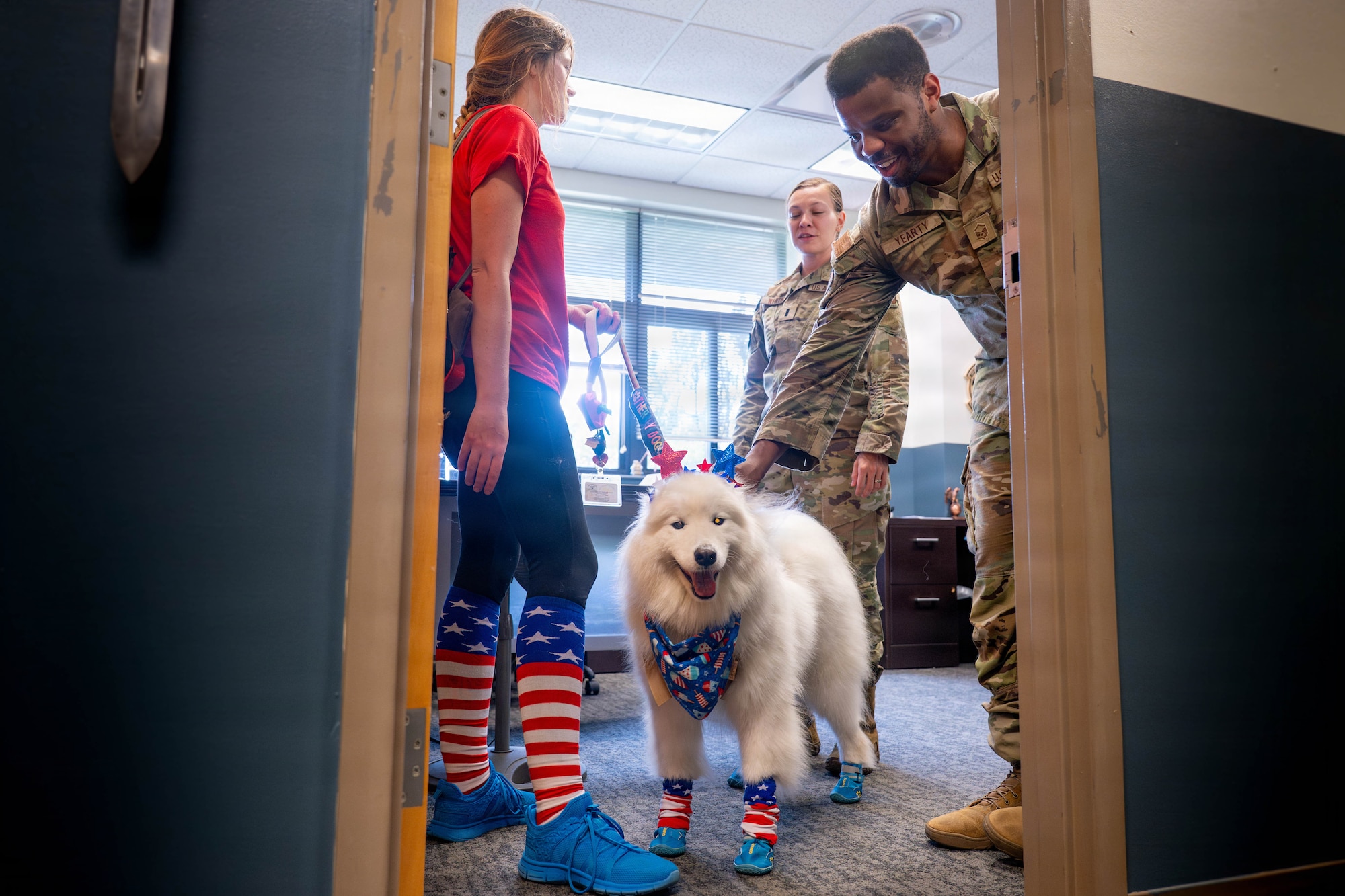 A photo of three people and a dog standing in a room together.