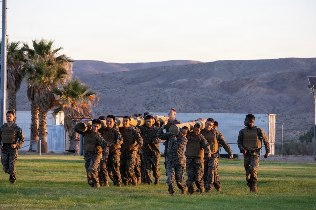U.S. Marines and a U.S. Navy Sailor participate in a log run and practice martial arts techniques during a Marine Corps Martial Arts Program Gray Belt Advancement Course at Sorenson Field aboard Marine Corps Logistics Base Barstow, California, July 10. The early-morning training, which integrated students and staff from the Lance Corporal Seminar, focused on combat conditioning, knife techniques, and weapons of opportunity to build physical discipline and fulfill belt progression requirements.