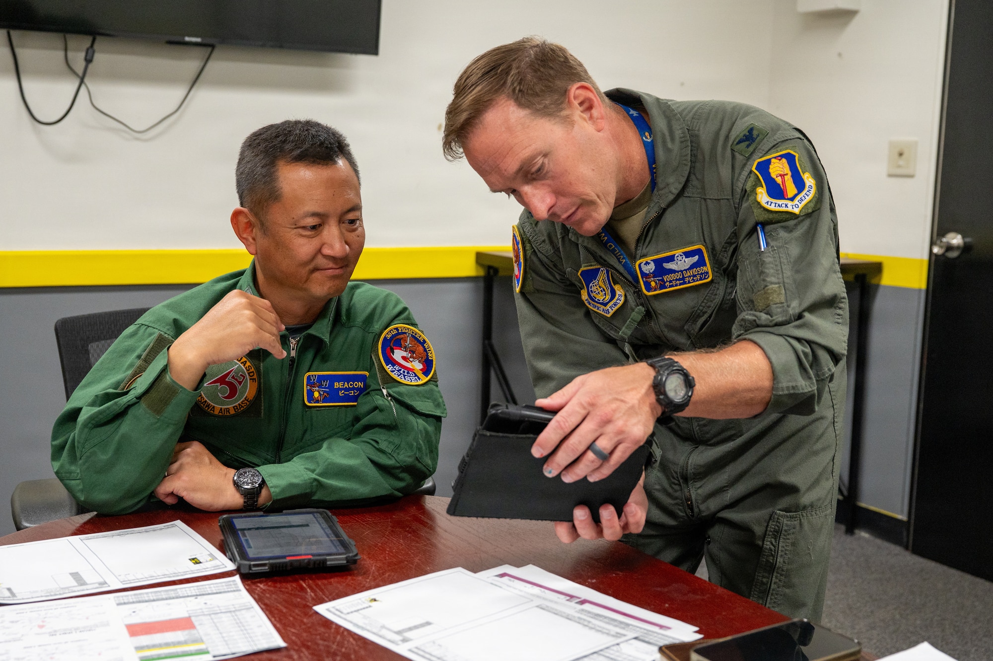 U.S. Air Force Col. Paul “Voodoo” Davidson, 35th Fighter Wing commander, right, reviews flight planning materials with Japan Air Self-Defense Force (JASDF) Maj. Gen. Teru “Beacon” Tomikawa, 3rd Air Wing commander, before a familiarization flight at Misawa Air Base, Japan, June 30, 2026