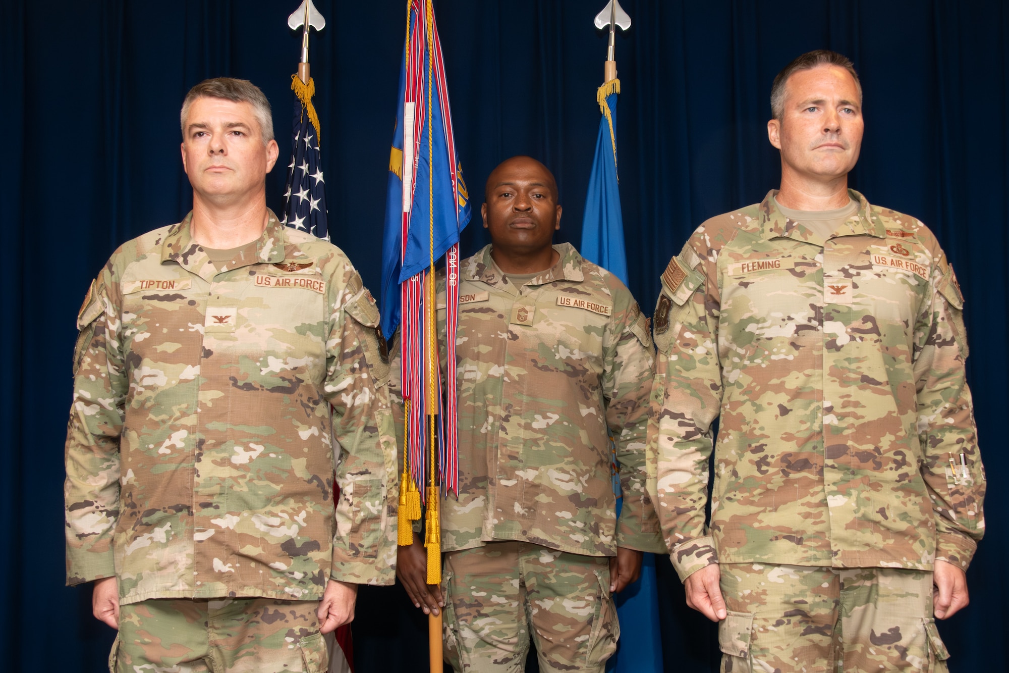 Three service members stand at attention during an assumption of command ceremony