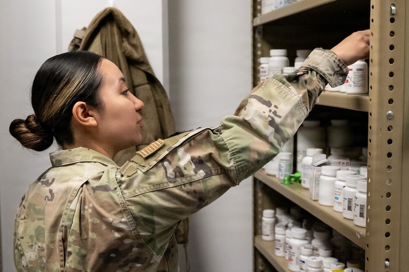 Service member reaches into medicine cabinet at a military pharmacy