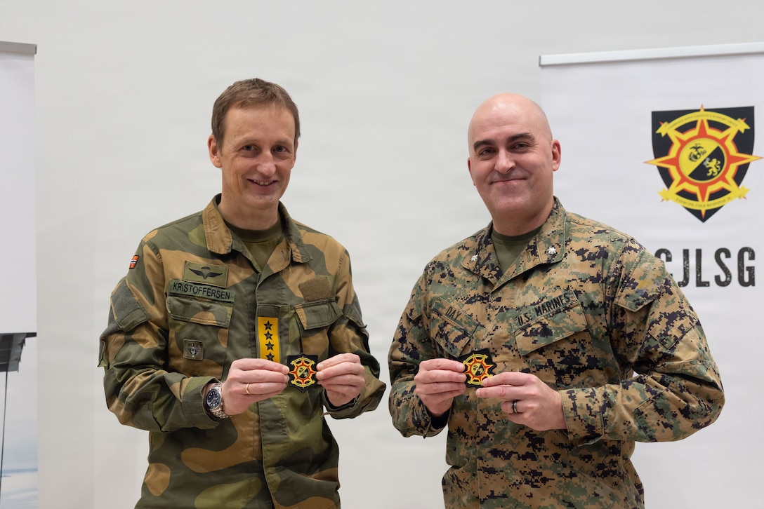 Norwegian army Chief of Defence Gen. Eirik Kristoffersen, left, and U.S. Marine Corps Lt. Col. Sean Day, the deputy chief of staff for the Combined Joint Logistics Support Group, hold patches during a tour of the CJLSG prior to exercise Cold Response 26 in Kjeller, Norway, Feb. 23, 2026. A key component of NATO's enhanced vigilance activity Arctic Sentry, exercise Cold Response 26 is a Norwegian-led winter military exercise designed to enhance collective defense capabilities and ensure U.S. readiness to rapidly deploy and seamlessly operate alongside NATO Allies in challenging arctic conditions. (U.S. Marine Corps Photo by Sgt. Rafael Brambila-Pelayo)