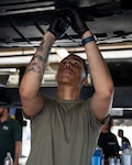 U.S. Army Pfc. Avontae Griffin, Alpha Company, Medical Readiness Battalion surgical technologist, removes the underbody splash shield from his vehicle to access the oil drain plug during a hands-on vehicle maintenance workshop at the Joint Base San Antonio-Lackland Auto Hobby Shop, June 17, 2026. The workshop supported mission readiness by helping service members build practical maintenance skills, improve personal vehicle reliability and reduce barriers to getting to the mission. (U.S. Air Force photo by Jonathan R. Mallard)