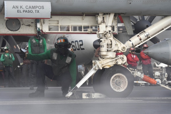 Aviation Boatswain's Mate (Equipment) 3rd Class Darius Jarmon assists an F/A-18 Super Hornet load onto a catapult on the flight deck aboard the Nimitz-class aircraft carrier USS Harry S. Truman (CVN 75).