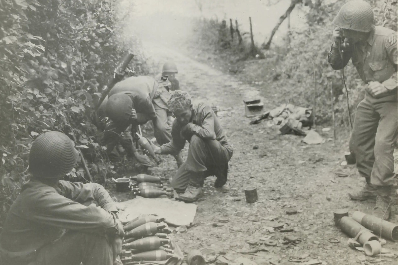 Soldiers on a dirt road operate weapons and a field radio.