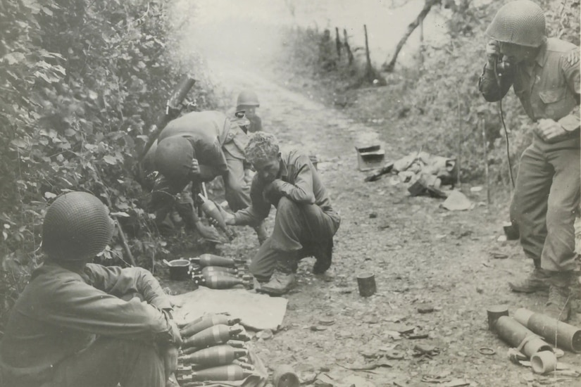 Soldiers on a dirt road operate weapons and a field radio.