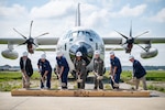 Coast Guard breaks ground on new runway with a Coast Guard HC-130J airplane in the background.
