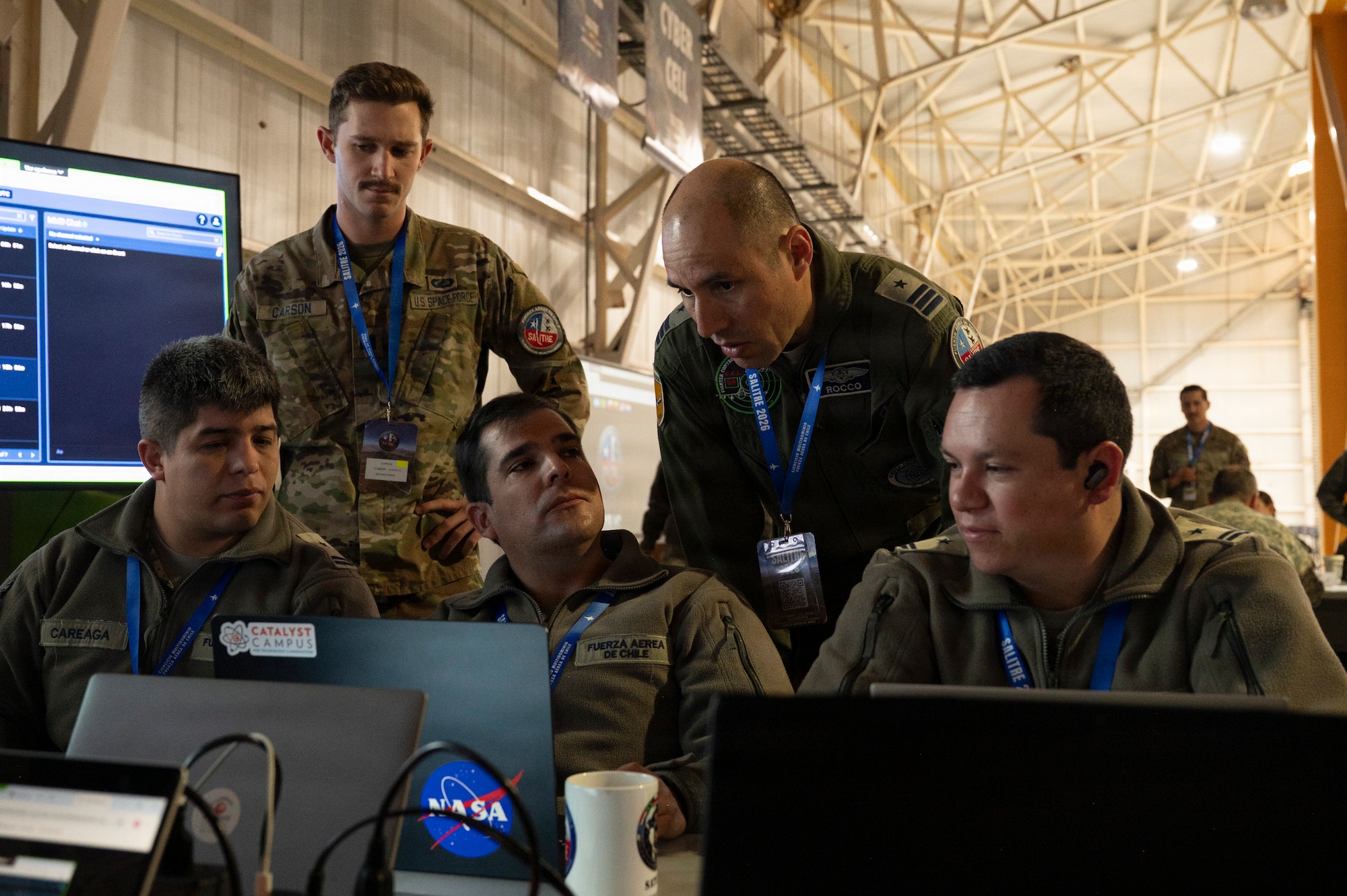A Chilean air force member stands over other Chilean service members while speaking, with a U.S. Space Force member.