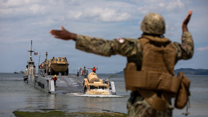 A U.S. Navy seaman uses hand signals to guide a Humvee offloading from a transport vessel at Pohang Port, South Korea, during CJLOTS 2026.