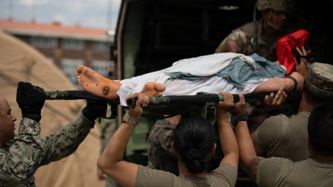 U.S. service members unload a simulated casualty on a litter from a Humvee 2-CT Ambulance during a CJLOTS 2026 exercise at Pohang Port, South Korea.