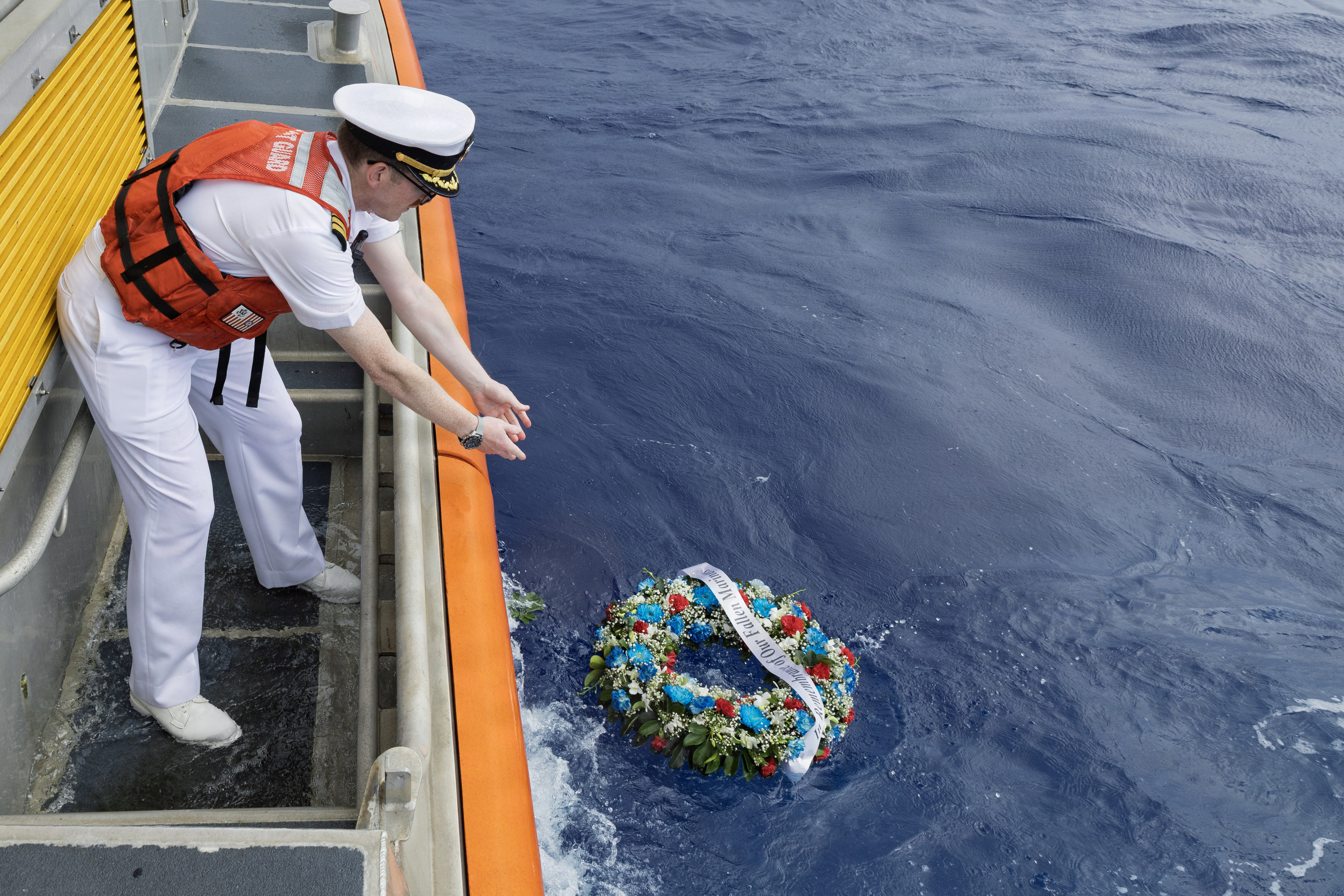 Cmdr. Paul J. Tortora, commanding officer, Military Sealift Command Ship Support Unit Guam lowers a wreath into the ocean off the coast of Naval Base Guam during a National Maritime Day commemoration to honor all fallen civilian mariners, May 22, 2026.